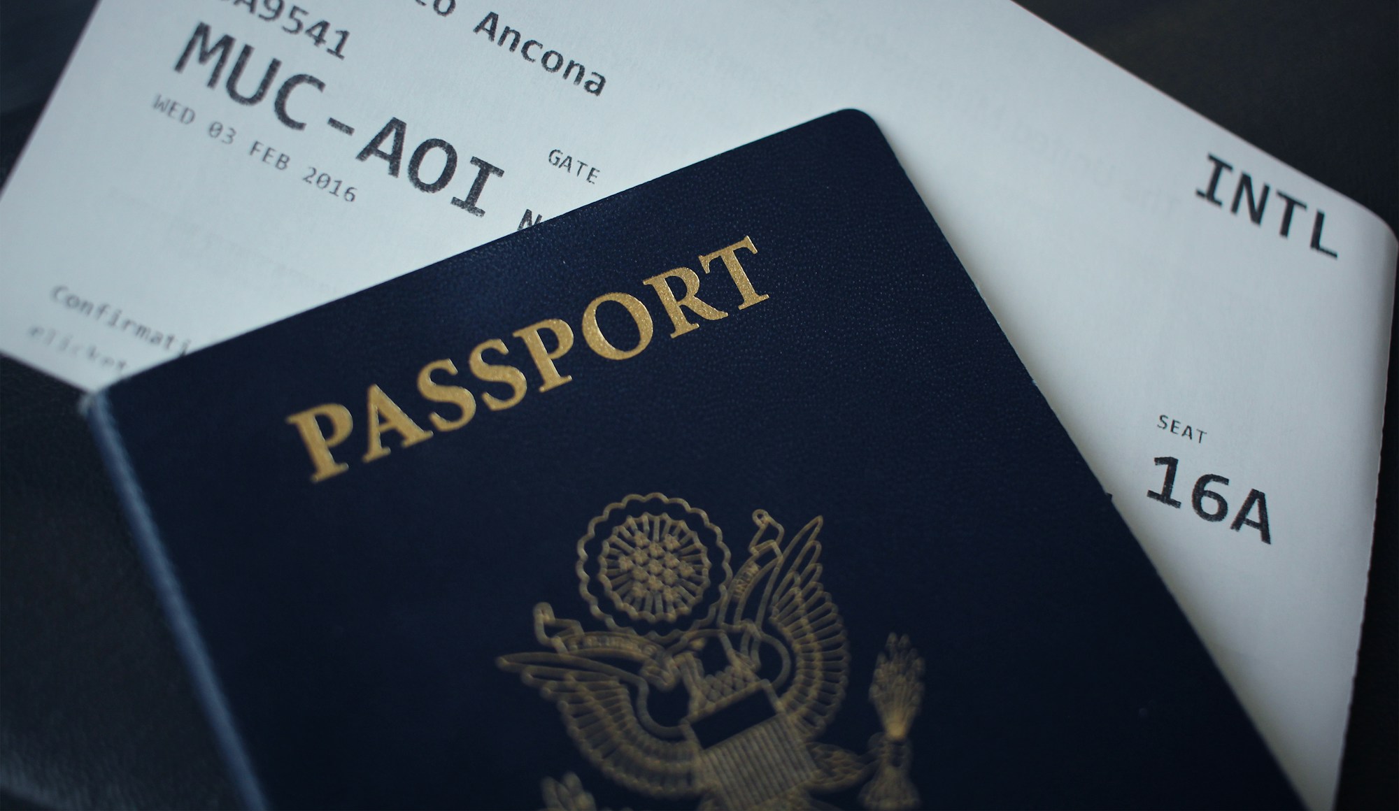Passport and boarding pass on a desk beside a notebook